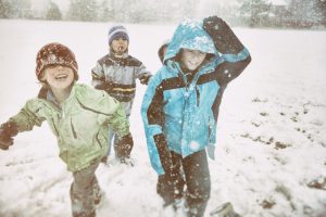 Laughing children playing in snow storm on a school field